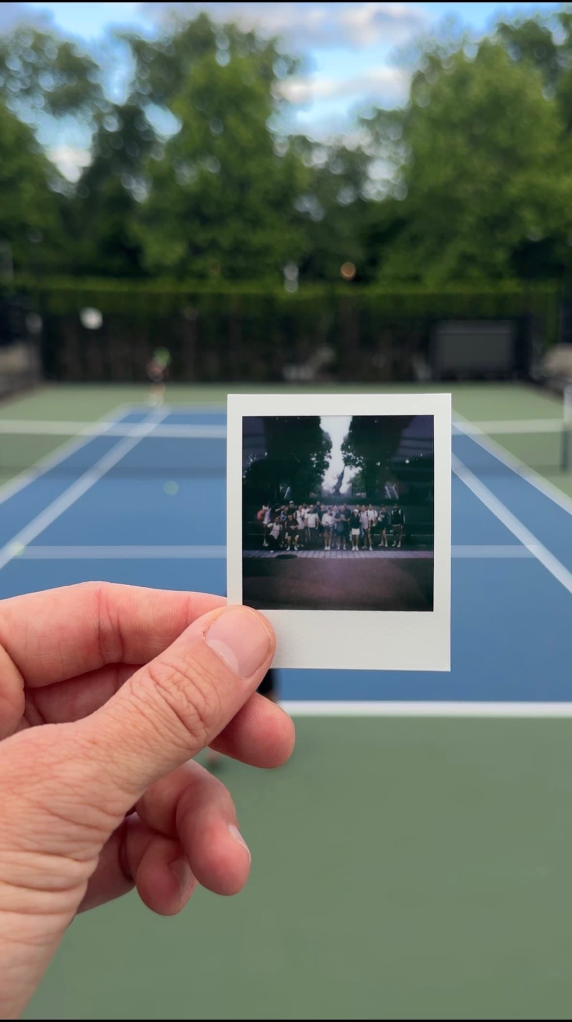 A polaroid of the Deuce crew, held up in front of a court