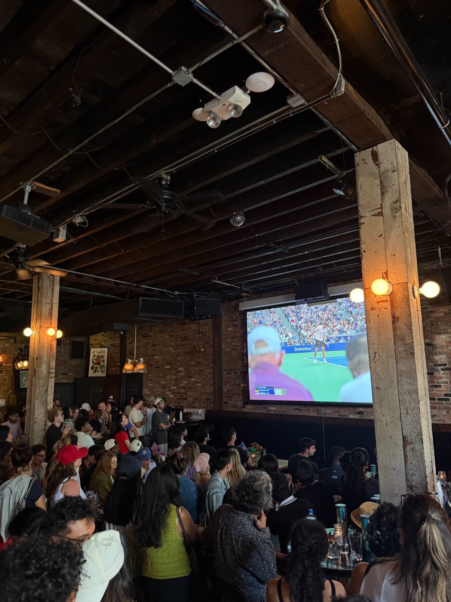 A packed bar watching the US Open on a projector screen